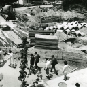 Students walk by a fence positioned around the site of the former College Bookstore, built in 1934, at Appalachian State Teachers College (1929–1967) after its demolition in 1967. The Education Building, built in 1925, can be seen in the background. In addition to renting and selling textbooks, the College Bookstore also provided Appalachian merchandise, supplies and refreshments, while the second floor provided space for three apartments. A snack bar was added in 1955. In 1967, the building was demolished