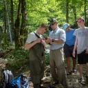 Professor Shea Tuberty, second from left, assists Eli Fried, a student at Chapel Hill High School, with his waders. Andrew Degele, far right, a student at Cardinal Gibbons High School in Raleigh, and Salil Pai, a student in the Early College at Guilford Community College, observe. Photo by Marie Freeman