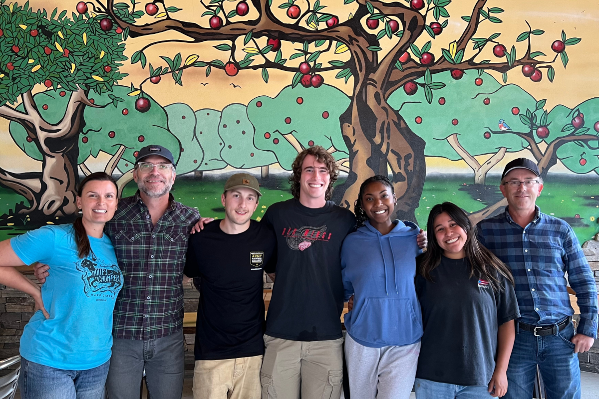 Fermentation Sciences majors Rhett Pressley (fourth from left), Myanna Green (fifth from left), and Carolina Morales (sixth from left) visited Molley Chomper in Lansing to learn about making cider. While there, they met with founder and lead cider maker Kate Arscott, co-founder and orchardist Tim Arscott, and cidermaker Kyle Haas.
