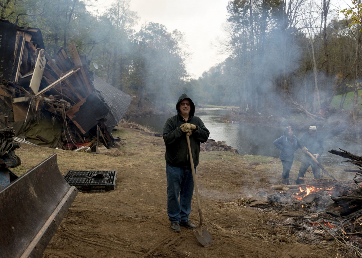 Eric Farmer burns a pile of debris at his destroyed home along the North Fork New River in Creston, NC on October 15. Farmers dad had built the house in 1965. Three hours before a mobile home came floating down the river that took out his home, Farmer and his wife had evacuated to higher ground to escape the rising flood waters. By his estimate the water rose 23 feet, taking 25 feet of riverfront property with it that used to be his backyard. Farmer didn’t have flood insurance that was priced at $1,900 a month for his home. He plans to rebuild and continue to live here. Photo by Barber (jesse-barber.com)