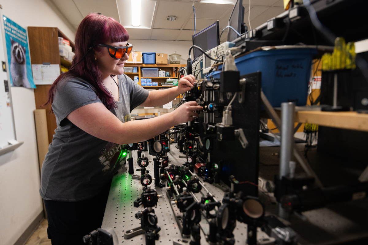 Junior applied physics major Aidan Lindsey, of Asheville, aligning one of the position detection lasers in the custom-built photonic force microscope and optical tweezers apparatus. Photo by Chase Reynolds