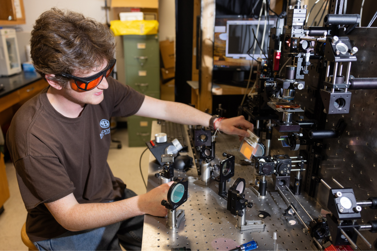 Senior physics and mathematics major Asher Rockriver, of Pittsboro, demonstrates the Raman excitation laser beam alignment procedure he developed for the Laser Tweezers Raman Spectroscopy system. Photo by Chase Reynolds
