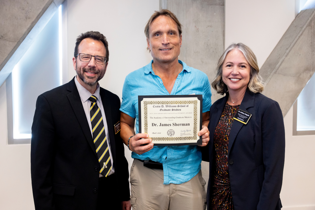 Department of Physics and Astronomy professor James Sherman, center, is presented the 100 Scholars Award and inducted into the Academy of Outstanding Mentors during the Cratis D. Williams School of Graduate Studies Faculty and Student Awards Ceremony on Tuesday, April 7, 2026. (Photo by Kyla Willoughby)