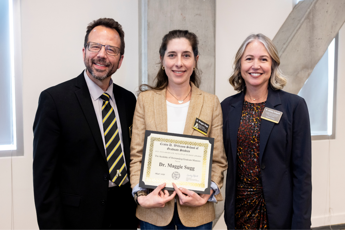 Department of Geography and Planning associate professor Maggie Sugg, center, is presented the 100 Scholars Award and inducted into the Academy of Outstanding Mentors during the Cratis D. Williams School of Graduate Studies Faculty and Student Awards Ceremony on Tuesday, April 7, 2026. (Photo by Kyla Willoughby)