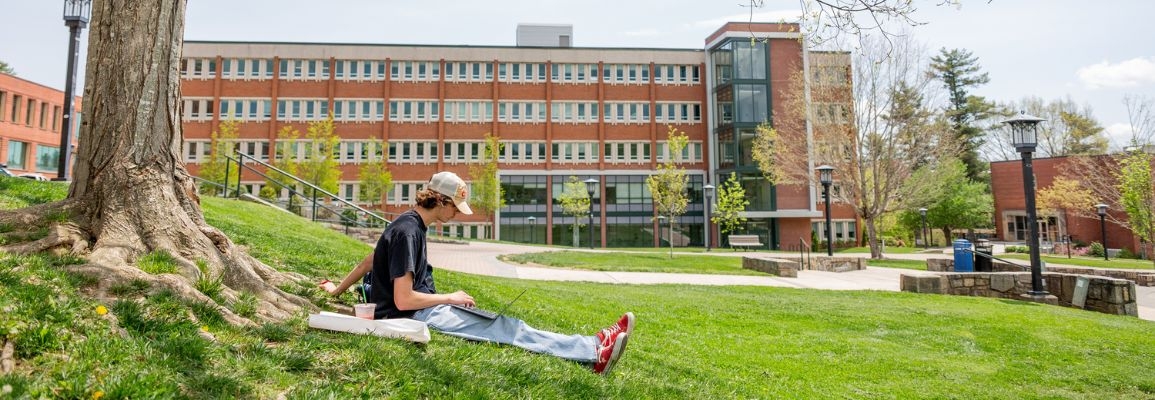 A student uses their laptop on Sanford Mall.