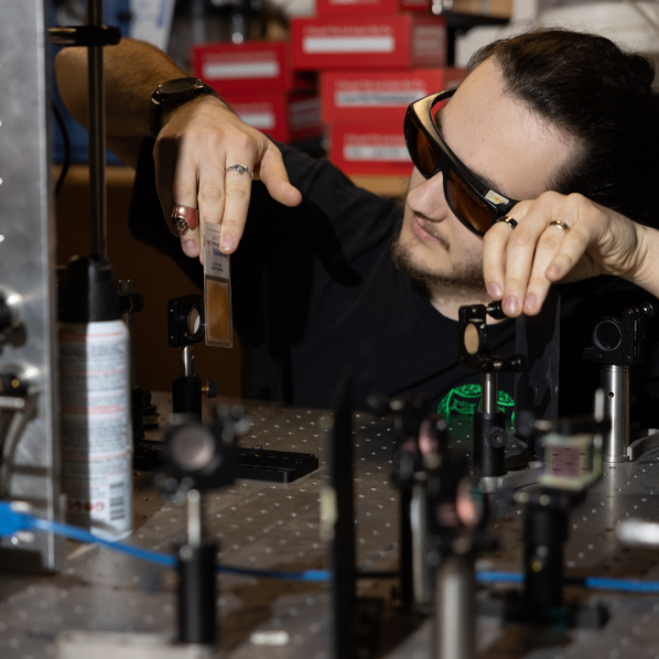 A man wearing goggles holds a card in front of a sensor.