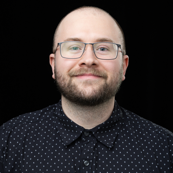 A headshot of College of Arts and Sciences Advising and Support Services Hub (CASSH) Assistant Director Dusty Roberts ’20 ’22. The background is black and Roberts is wearing glasses and a dark shirt featuring white dots.
