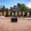 Displayed in front of the Appalachian State University sign, located in Founders Plaza on App State’s campus, are the university mace and banner, along with the banners for App State’s College of Arts and Sciences, Beaver College of Health Sciences, College of Fine and Applied Arts, Hayes School of Music, Reich College of Education, Walker College of Business and Cratis D. Williams School of Graduate Studies. The state flag is shown at far right and the U.S. flag is pictured at far left. Photo by Marie Free