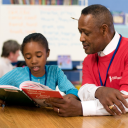 A Foster Grandparent Program volunteer assists a child with reading.