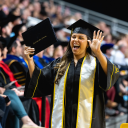 An App State graduate waves to family and friends after walking across the stage at the Spring 2024 Commencement for App State’s College of Arts and Sciences on May 11. Photo by Kyla Willoughby