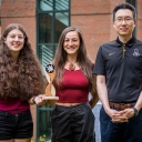 Grace Waugh, a senior sustainable technology major from Chapel Hill, far left, and Summer Gee ’20, a graduate student from Wrightsville Beach, center, were part of a multidisciplinary team of App State undergraduate and graduate students that won second place in its division in the 2021–22 U.S. Department of Energy Solar District Cup. Waugh and Gee are pictured holding the trophy that the team received and with the team’s faculty adviser, Dr. Jaewon Oh, assistant professor in the Department of Sustainable T
