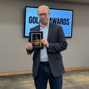 Dr. Karl Campbell, professor in the Department of History, holds his Professor of the Year Goldie Award.