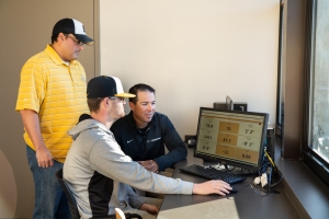 Dr. Rene Salinas, professor of Mathematical Sciences (left), with head coach of the baseball team, Kermit Smith and sophomore Cameron Lyons talk stats looking at Trackman data from the previous game. Photo by Ellen Gwin Burnette