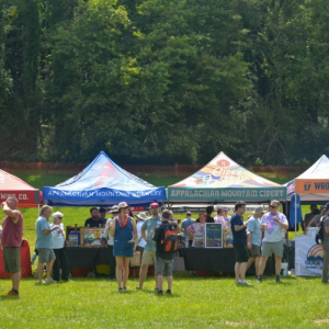 Tents with people drinking beer in front of them.