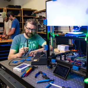 Dr. Zachary Russell, assistant professor in the Department of Physics and Astronomy at App State, center, works with student researchers Ethan Humphries, a senior in physics major from Kings Mountain, and Hunter Corman ’24, an engineering physics graduate student from Morehead City, pictured in the background, in the Ion Innovations Scientific Instrumentation Development Lab in Boone to assemble 3D-printed components for rapid prototyping of microscope designs. Russell has been awarded a $2.3 million grant 