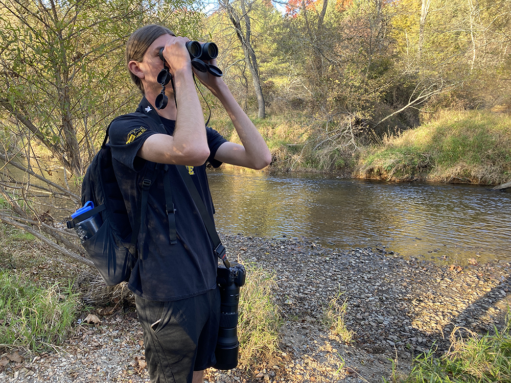 Will Bennett, a senior geography major, identifies a bird at the Boone Greenway. Photo submitted by Marta Toran.